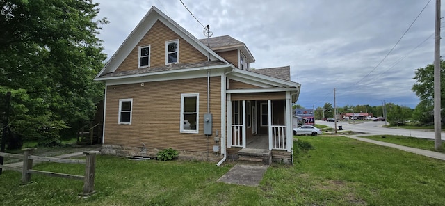 rear view of house with a shingled roof and a yard