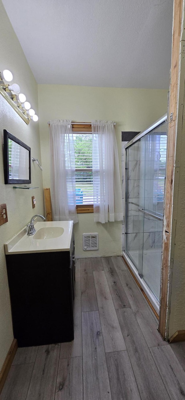 full bathroom featuring a stall shower, visible vents, wood finished floors, and vanity