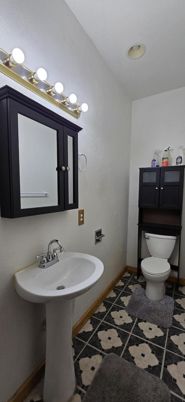bathroom with baseboards, tile patterned floors, and toilet