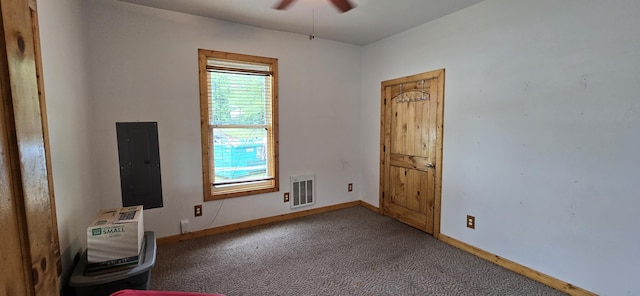 carpeted spare room featuring visible vents, baseboards, ceiling fan, and electric panel