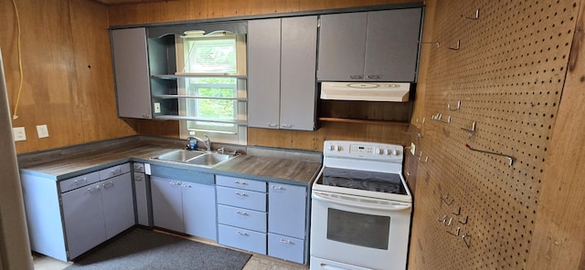 kitchen with wood walls, a sink, gray cabinetry, white electric range oven, and under cabinet range hood
