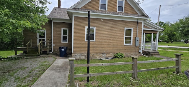 view of side of property with fence, a shingled roof, and a yard