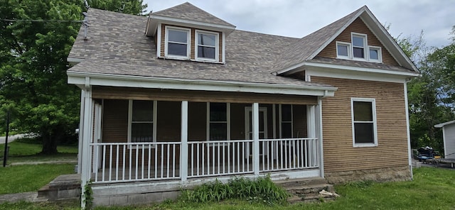 rear view of property with a sunroom, a shingled roof, and a yard
