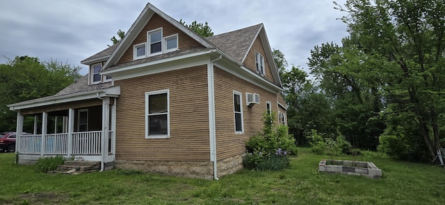 view of home's exterior with a lawn, a wall unit AC, and roof with shingles