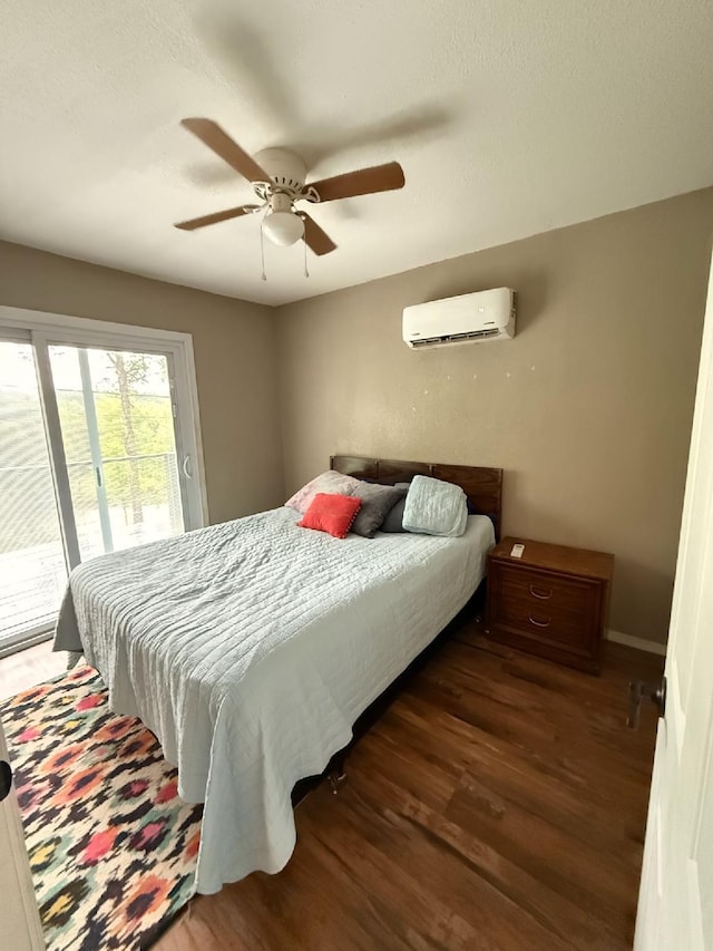 bedroom featuring a wall mounted AC, a ceiling fan, wood finished floors, and access to exterior