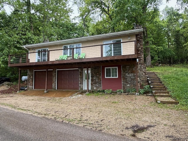 view of front of home featuring a garage, stairs, stone siding, and dirt driveway