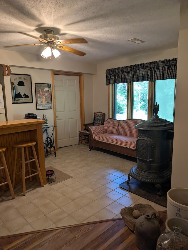 249 Mount Vernon Rd, Forsyth, MO 65653 - living room featuring ceiling fan, a bar, a wood stove, and a textured ceiling