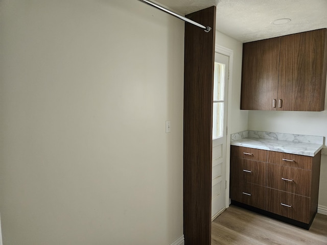 bar with baseboards, light wood finished floors, and a textured ceiling