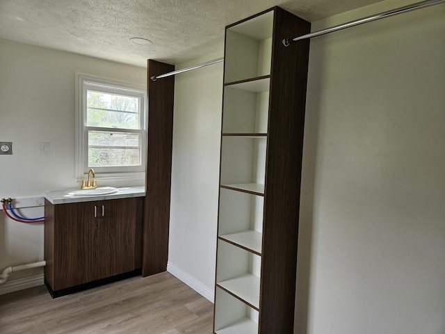interior space featuring vanity, baseboards, a textured ceiling, and wood finished floors