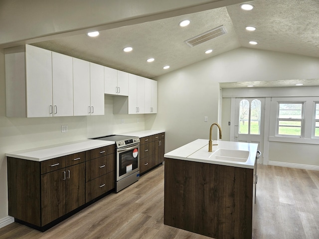 kitchen with visible vents, white cabinetry, a sink, light wood finished floors, and stainless steel range with electric cooktop