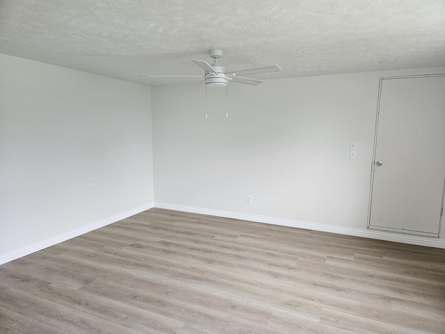 empty room featuring light wood-style floors, baseboards, ceiling fan, and a textured ceiling