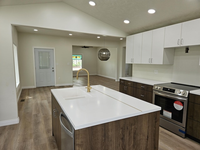 kitchen with white cabinets, dark brown cabinetry, appliances with stainless steel finishes, a sink, and vaulted ceiling