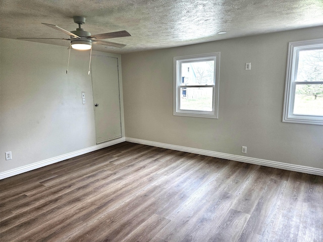 unfurnished room with baseboards, a textured ceiling, a wealth of natural light, and wood finished floors