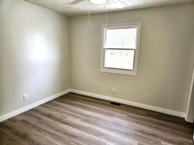 spare room featuring dark wood-style flooring, baseboards, and visible vents