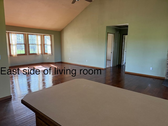 unfurnished room with a ceiling fan, baseboards, wood finished floors, and high vaulted ceiling