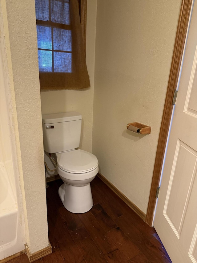 full bath featuring baseboards, a textured wall, toilet, and hardwood / wood-style floors