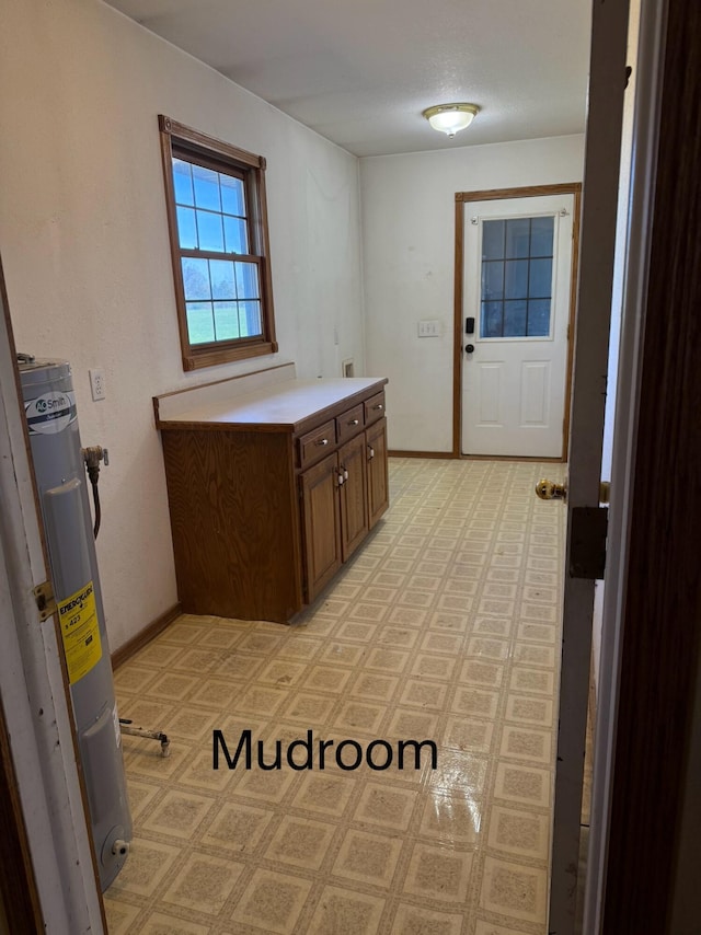 interior space with baseboards, light floors, and electric water heater