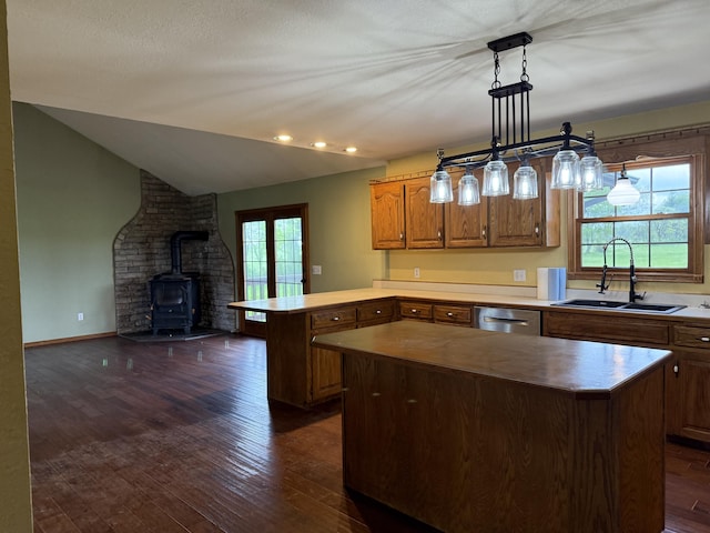 kitchen featuring a kitchen island, a wood stove, a sink, a peninsula, and dark wood-type flooring