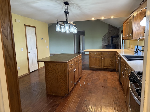 kitchen with dark wood-style flooring, a wood stove, brown cabinetry, a peninsula, and gas range oven