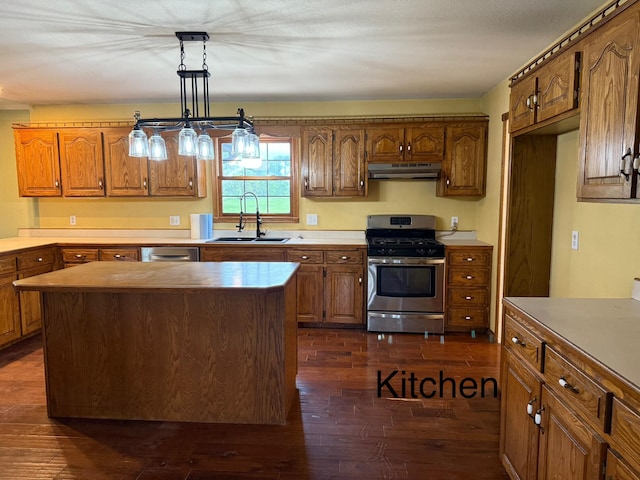 kitchen featuring brown cabinetry, dark wood-style floors, under cabinet range hood, a sink, and appliances with stainless steel finishes