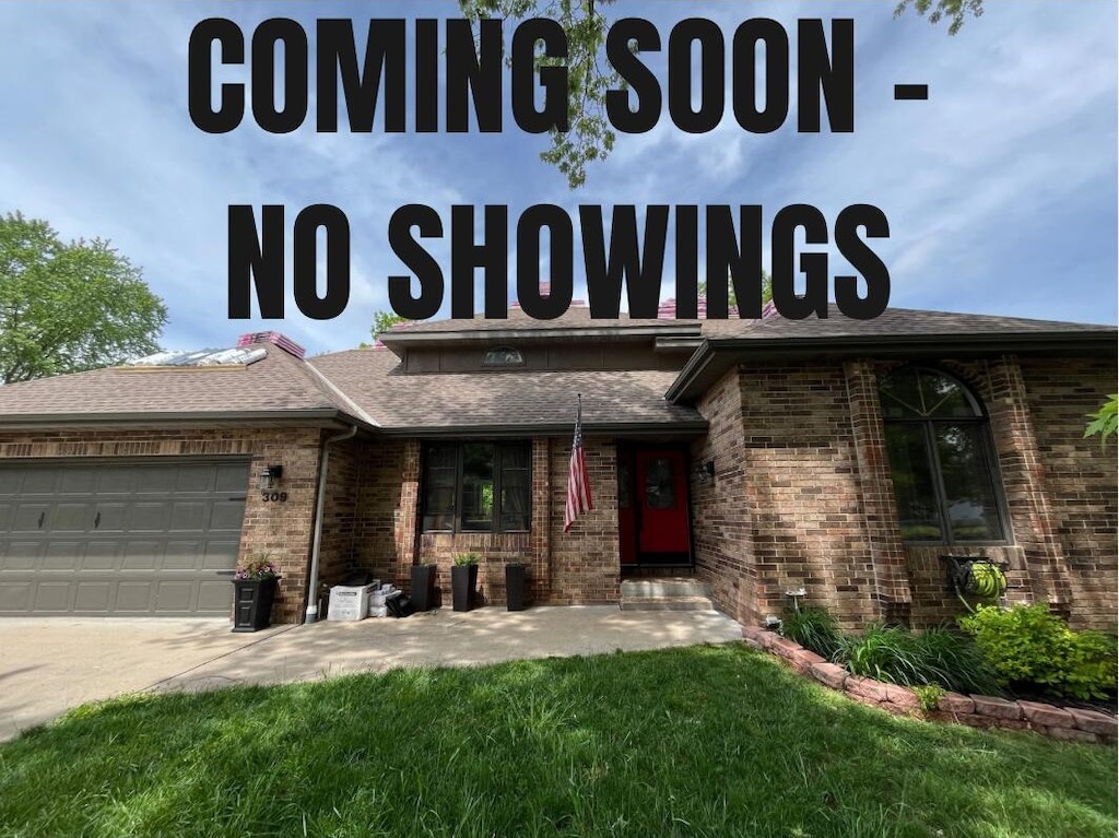 exterior space featuring roof with shingles, an attached garage, brick siding, concrete driveway, and a front lawn