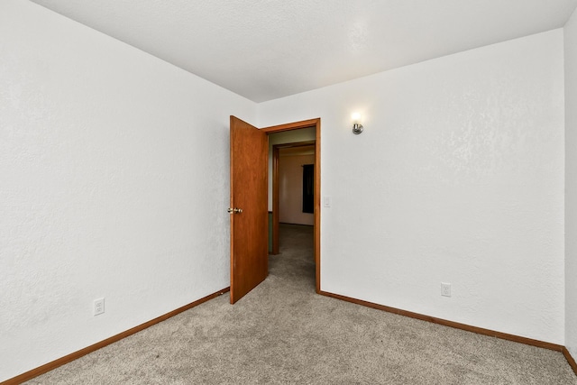 carpeted spare room featuring baseboards