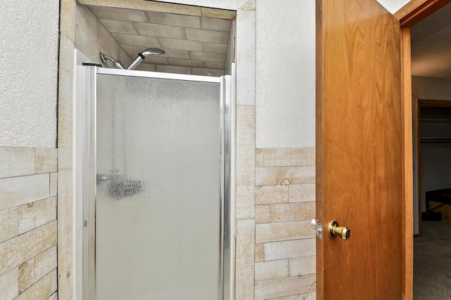 bathroom featuring a textured wall and a stall shower