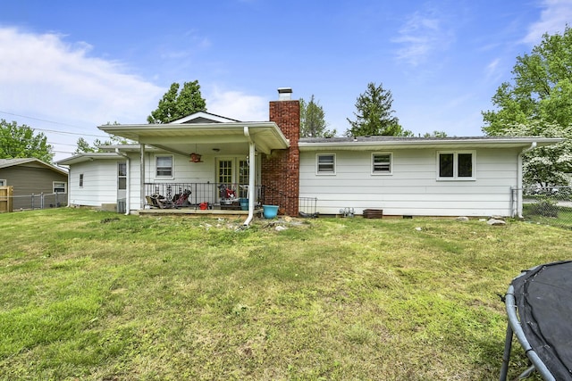 back of house with fence, a chimney, and a yard