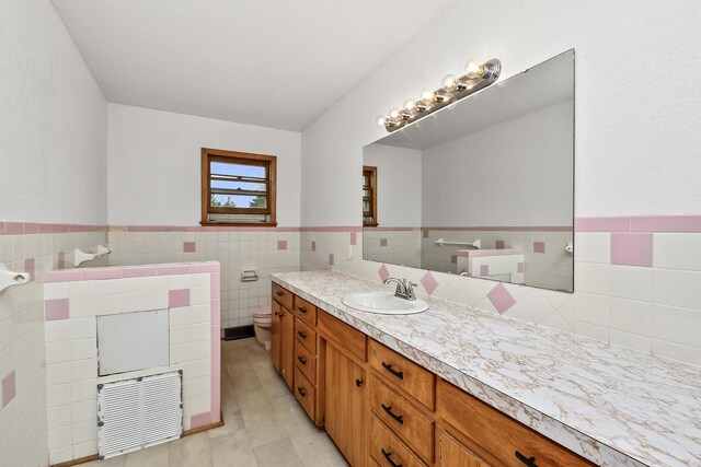 bathroom featuring visible vents, tile walls, tile patterned flooring, vanity, and a wainscoted wall