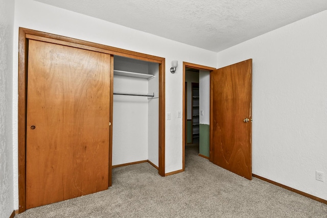 unfurnished bedroom with carpet floors, a textured ceiling, baseboards, and a closet