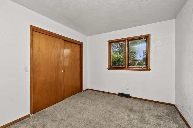 unfurnished bedroom with carpet floors, a closet, a textured ceiling, and visible vents