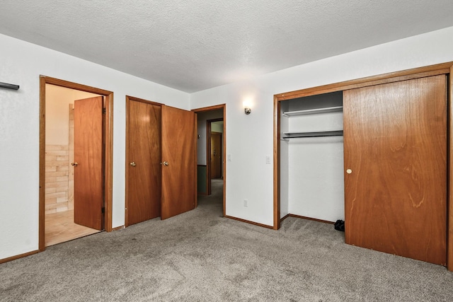 unfurnished bedroom featuring baseboards, carpet flooring, a textured ceiling, and ensuite bath