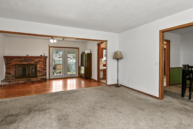 unfurnished living room featuring a fireplace, carpet floors, a textured ceiling, a ceiling fan, and baseboards
