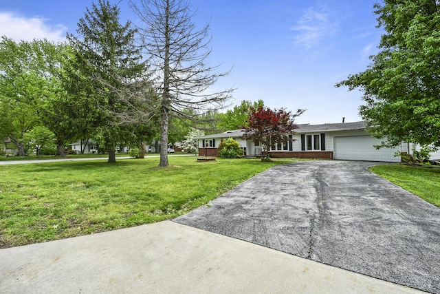view of front of house featuring brick siding, a garage, a front yard, and aphalt driveway
