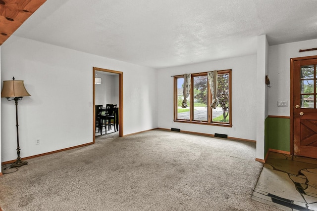 unfurnished living room with baseboards, carpet, and a textured ceiling