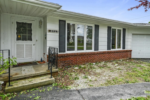 doorway to property with an attached garage and brick siding