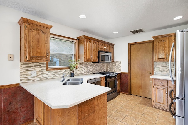 kitchen featuring visible vents, a peninsula, light countertops, a sink, and appliances with stainless steel finishes