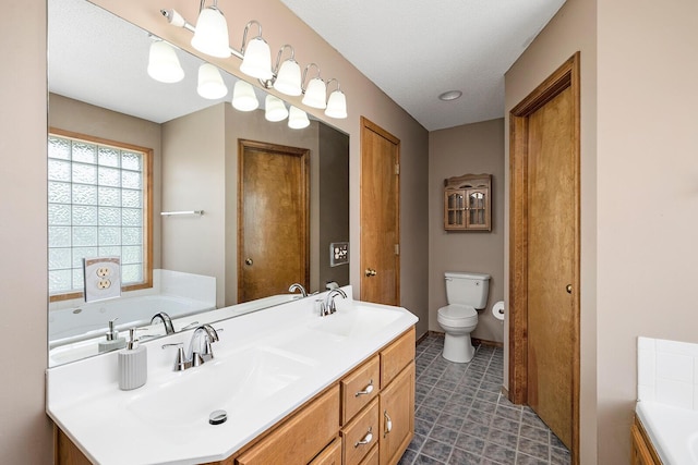 bathroom featuring double vanity, a sink, a bath, and toilet