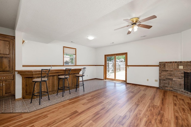 bar with a ceiling fan, baseboards, a wealth of natural light, and light wood-style floors