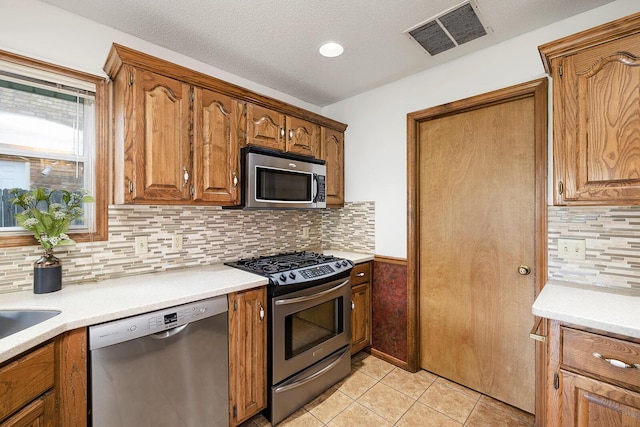 kitchen featuring visible vents, light countertops, light tile patterned floors, appliances with stainless steel finishes, and backsplash