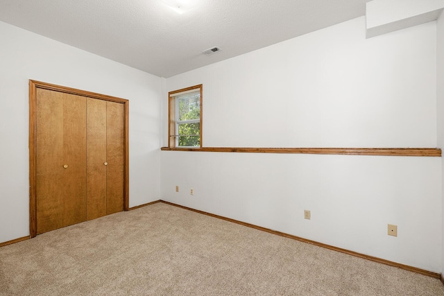 unfurnished bedroom with carpet flooring, baseboards, visible vents, and a closet