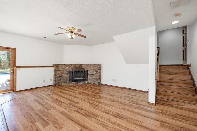 unfurnished living room with ceiling fan, visible vents, light wood-type flooring, stairway, and baseboards