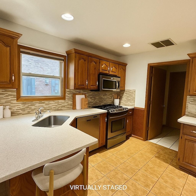 3934 W Lark St, Springfield, MO 65810 - kitchen featuring stainless steel appliances, backsplash, light countertops, light tile patterned flooring, and a kitchen bar
