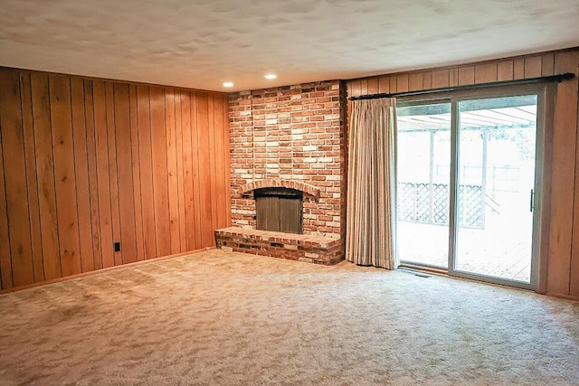 706 W Katella Ct, Springfield, MO 65807 - unfurnished living room featuring visible vents, a brick fireplace, wood walls, and carpet flooring