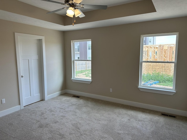 carpeted empty room with baseboards, visible vents, and ceiling fan
