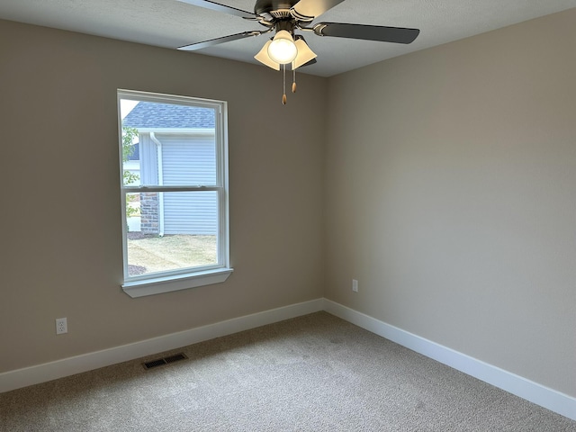 carpeted empty room with visible vents, baseboards, and ceiling fan