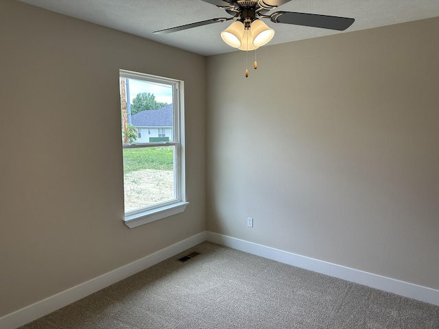 empty room with visible vents, baseboards, light colored carpet, a textured ceiling, and a ceiling fan