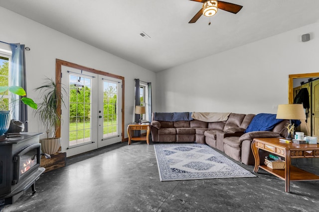living area with a wood stove, concrete floors, a ceiling fan, and a healthy amount of sunlight