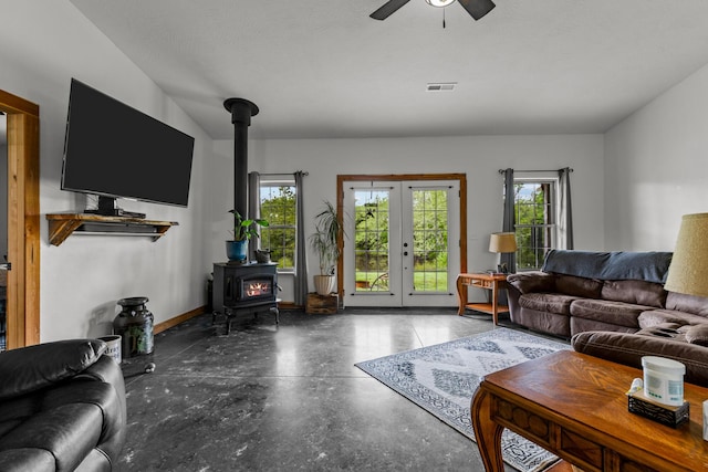 living room with ceiling fan, concrete floors, a wealth of natural light, and a wood stove
