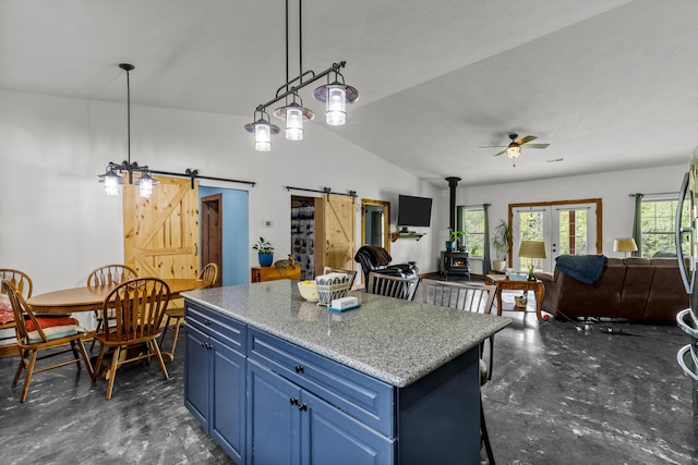 kitchen featuring ceiling fan, a barn door, a wood stove, a kitchen island, and blue cabinets